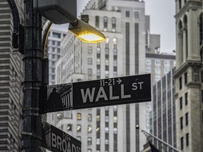 A street light brightens a Wall Street sign outside the New York Stock Exchange, Monday, Oct. 3, 2022, in New York. Stocks are off to a mostly higher start on Wall Street, Tuesday, Oct. 25, as traders take in a big round of earnings reports from big U.S. companies.