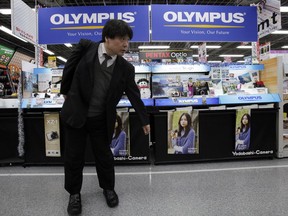 FILE - A shopper walks by a sales counter of Olympus cameras at a store in Tokyo on Dec. 8, 2011. Japanese medical equipment maker Olympus said Friday, Oct. 21, 2022 it has named as its chief executive Stefan Kaufmann, a German who has worked for two decades at the manufacturer once known for old-style photographic cameras.