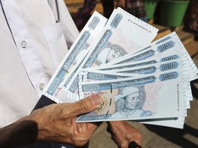 FILE - A man shows currency notes imprinted with portrait of Gen. Aung San, late father of Myanmar leader Aung San Suu Kyi, outside Myanmar Economic Bank on Jan. 7, 2020, in Yangon, Myanmar. Myanmar's central bank has promised improvements and warned against currency manipulation after an international watchdog put the military-controlled country on a terrorism and financial crimes blacklist.