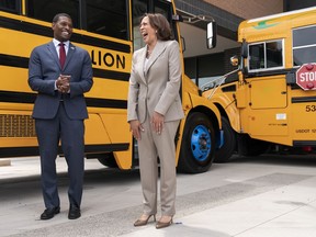 FILE - Vice President Kamala Harris, right, laughs with Environmental Protection Agency Administrator Michael Regan, during a tour of electric school buses at Meridian High School in Falls Church, Va., May 20, 2022. Nearly 400 school districts spanning all 50 states are receiving grants totaling nearly $1 billion to purchase nearly 2,500 "clean" school buses under a new federal program. The Biden administration is making the grants available as part of a wider effort to accelerate the transition to zero emission vehicles and reduce air pollution near schools and communities.