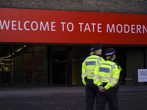 Police officers patrol the entrance of Tate Modern gallery, in London, Saturday, Oct. 15, 2022. Climate protesters threw soup over Vincent van Gogh's "Sunflowers" in London's National Gallery on Friday to protest against fossil fuel extraction, but no damage was caused to the glass-covered painting.