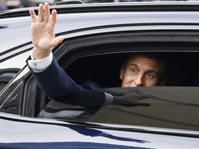 French President Emmanuel Macron waves as he leaves in a car after a visit for the commemorative century exposition of the opening of the Grande Mosque of Paris, in Paris, Wednesday Oct. 19, 2022.