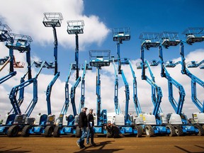 People walk through a row of boom lifts during the Ritchie Bros. auction in Nisku, Alta., on Tuesday, April 26, 2016.