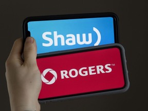 A woman holds phones displaying Rogers and Shaw logos.