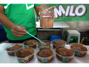 An employee pours Milo on bowls of crushed ice while preparing orders of "Milo on round ice" snack at an Es Kepal Milo Viral street stall in the Tebet area of Jakarta, Indonesia, on Thursday, July 12, 2018. Cocoa production in the 130-year old industry in Indonesia is set to shrink for the third straight year as farmers switch to other crops and annual per capita consumption of chocolate languishes. That might just be about to change, though, thanks to a Millennial re-imagining of the chocolate-malt drink Milo - one of the region's favorite treats - into Es Kepal Milo, which translates as "Milo on round ice."