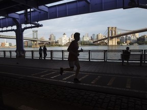 People jog along the East River running path in New York, U.S., on Wednesday, July 8, 2020. In New York, with all in-person running events cancelled for the foreseeable future, virtual racing is booming.