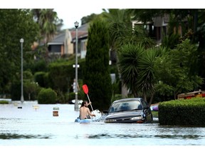 A local resident paddles past a submerged car in the suburb of McGraths Hill in Sydney, Australia, on Wednesday, March 24, 2021. The one-in-100 year flooding event in recent days is causing supply disruptions in Australia.