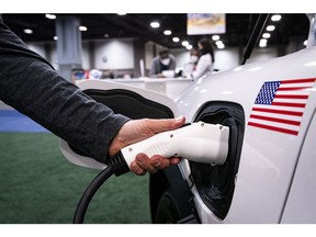 An exhibitor demonstrates plugging in a charging port for a Ford Motor Co. Mustang during the Washington Auto Show in Washington, D.C., U.S., on Friday, Jan. 21, 2022. The auto show, designated as one of the nation's top five auto shows by the International Organization of Motor Vehicle Manufacturers, runs from January 21-30.