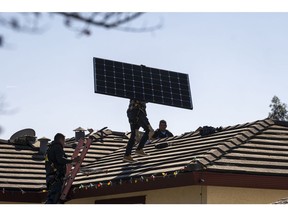 Save A Lot Solar contractors carry LG Electronics solar panels onto the roof of a home in Hayward, California, U.S., on Tuesday, Feb. 8, 2022. California regulators are delaying a vote on a controversial proposal to slash incentives for home solar systems as they consider revamping the measure. Photographer: David Paul Morris/Bloomberg