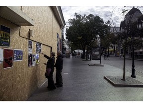 Pedestrians look at flyers posted on a boarded up business in central Odesa, Ukraine, on Thursday, Sept. 29, 2022. The threat of Russian strikes with Iranian Shahed-136 drones has hurt already struggling local businesses and created issues at the port, Odesa Mayor Gennadiy Trukhanov said.
