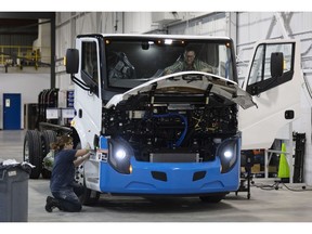 Workers complete a Lion 6 electric truck at the Lion Electric assembly plant in Saint-Jerome, Quebec, Canada, on Thursday, Oct. 13, 2022. Lion Electric Co. designs, develops, manufactures, and distributes purpose-built all-electric medium and heavy-duty urban vehicles, including seven mid range truck and bus models.
