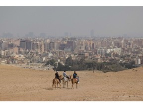 The city skyline of Cairo beyond horse riders on the Giza pyramid complex in Giza, Egypt, on Wednesday, Nov. 2, 2022. On November 6, leaders around the world will gather in Sharm el-Sheikh for the annual UN Climate Change conference, known this year as COP27. Photographer: Sima Diab/Bloomberg