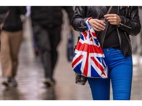 A shopper carries a shopping bag with a British Union flag design along Oxford Street in central London, UK, on Monday, Nov. 7, 2022. Prices in British shops rose by the highest rate since at least 2005 last month as the cost-of-living crisis piles pressure on consumers. Photographer: Jason Alden/Bloomberg