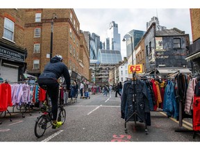 A cyclist passes empty clothing stalls at Petticoat Lane Market with the City of London skyline behind in London, UK, on Friday, Nov. 11, 2022. The UK economy shrank in the third quarter for the first time since the final lockdown of the pandemic as the cost of living crisis squeezed spending and the extra bank holiday for the Queen's funeral shut businesses. Photographer: Chris J. Ratcliffe/Bloomberg