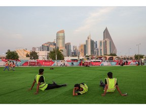 Workers rest on artificial grass outside a FIFA Fan Zone area in Doha, Qatar, on Friday, Nov. 18, 2022. The FIFA World Cup Qatar 2022 tournament has been beset with controversies, ranging from scheduling complications due to Qatar's summer heat to the treatment of migrant workers.