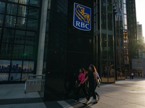 People walk past a Royal Bank of Canada sign in the financial district in Toronto on Tuesday, Sept. 20, 2022.