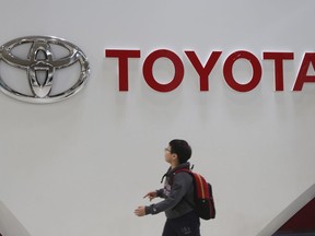 File - A boy looks up at the logo of Toyota Motor Corp. at its gallery in Tokyo, Jan. 15, 2020. Toyota said Tuesday, Nov. 1, 2022, that its profit fell 31% in the last quarter as a shortage of computer chips offset foreign exchange gains from a weaker yen.