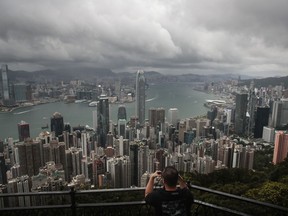 FILE - A visitor sets up his camera in the Victoria Peak area to photograph Hong Kong's skyline, Sept. 1, 2019. A tropic storm and absences of VIP guests have cast a shadow over Wednesday's planned financial conference meant to help Hong Kong restore its image as a financial hub and destination for business travel.