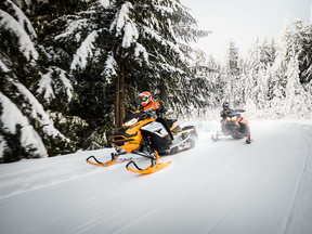 Ski-Doos riders in a snowy forest
