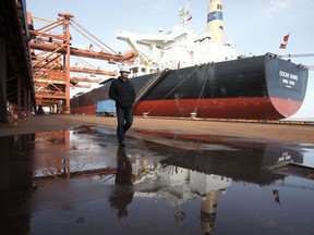 A worker walks near a bulk carrier cargo ship docked at a port in Shanghai, China.