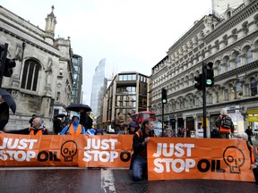 FILE - Activists from the group Just Stop Oil block a road in London, Thursday, Oct. 27, 2022 demanding to stop future gas and oil projects from going ahead. British climate activists who have blocked roads and splattered artworks with soup said Friday, Nov. 11, 2022, that they are suspending a days-long protest that has clogged a major highway around London.