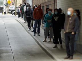 People wait in line outside a COVID-19 testing centre at St. Michael's Hospital in Toronto.