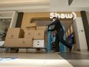 A worker pushes a cart past a Shaw Communications Inc. store in the CF Polo Park mall in Winnipeg, Man.
