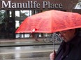 A pedestrian walks past the Manulife Place building in downtown Vancouver.