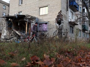 A local resident pushes his bicycle past a damaged residential building in the town of Lyman, Donetsk region, amid the Russian invasion of Ukraine.