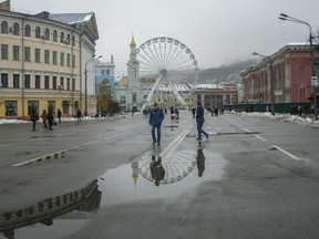 Pedestrians walk past a Ferris wheel in the Padolsky district of Kyiv amid the Russian invasion of Ukraine.