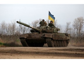Ukrainian servicemen ride a tank in eastern Ukraine on Nov. 24. Photographer: Anatoli Stepanov/AFP/Getty Images
