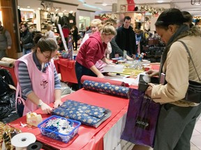 Volunteers from a local hospital wrap gifts for shoppers in a downtown Montreal shopping plaza, Wednesday, Dec 23, 2003. Young Canadians are looking for ways to cut back on spending this holiday season without having to scale back their gift-giving budgets.THE CANADIAN PRESS/Paul Chiasson