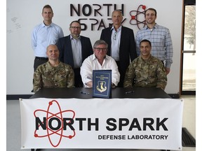 U.S. Air Force Col. Timothy Curry (front right), 319th Reconnaissance Wing commander, U.S. Air Force Lt. Col. Michael Dunn (front left), North Spark Defense Laboratory director, and the Bakken Energy Team pose for a photo Nov. 15, 2022, at the North Spark Defense Laboratory on Grand Forks Air Force Base, North Dakota. This agreement supports the Air Force commitment to implementing and funding ways to reduce energy consumption and meet federal energy goals. (U.S. Air Force photo by Senior Airman Roxanne Belovarac)