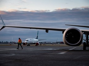 A ground worker walks under one of the wings of a WestJet Airlines Boeing 737 Max aircraft after it arrived at Vancouver International Airport, in Richmond, B.C., Thursday, Jan. 21, 2021. Canada's Transport Minister met with airlines and airports to ensure reliable service for travellers ahead of what is expected to be a busy travel season.