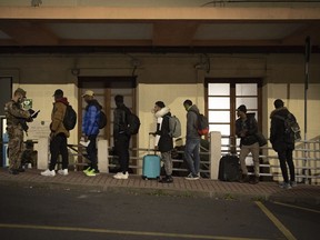 Migrants line up to be checked by Italian authorities at the Italian French border of Ventimiglia, Italy, Saturday, Nov. 12, 2022.