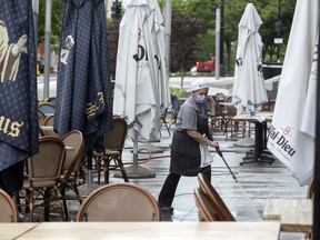 FILE - A worker at a restaurant along K Street in downtown Washington, power washes the outdoor seating area, May 27, 2020. A controversial proposal to change the pay structure for servers and other workers at Washington's bars and restaurants goes before voters Tuesday, Nov. 8, 2022.