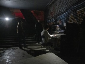 A person plays a piano in a street underpass during a blackout in Kyiv, Ukraine, Sunday, Nov. 6, 2022.
