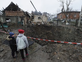 Children look at a crater created by an explosion in a residential area after Russian shelling in Solonka, Lviv region, Ukraine, Wednesday, Nov. 16, 2022.