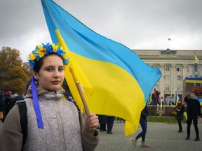 A young woman wearing a traditional folk flower wreath holds a Ukrainian flag in central Kherson, Ukraine, Sunday, Nov. 13, 2022. The Russian retreat from Kherson marked a triumphant milestone in Ukraine's pushback against Moscow's invasion almost nine months ago.