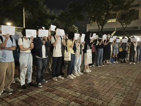 Protesters hold up blank white papers during a commemoration for victims of a recent Urumqi deadly fire at the Chinese University of Hong Kong in Hong Kong, Monday, Nov. 28, 2022. Students in Hong Kong chanted "oppose dictatorship" in a protest against China's anti-virus controls after crowds in mainland cities called for President Xi Jinping to resign in the biggest show of opposition to the ruling Communist Party in decades.