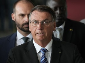 Brazilian President Jair Bolsonaro speaks from his official residence of Alvorada Palace in Brasilia, Brazil, Tuesday, Nov. 1, 2022, the leader's first public comments since losing the Oct. 30 presidential runoff. Behind his Bolsonaro's son Eduardo, a lawmaker.