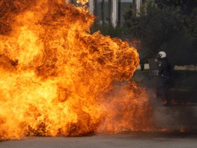 A Molotov cocktail explodes near riot police outside the Greek Parliament during clashes in Athens, Greece, Wednesday, Nov. 9, 2022. Thousands of protesters are marching through the streets of Athens and the northern Greek city of Thessaloniki as public and some private sector workers walk off the job for a 24-hour general strike against price hikes.