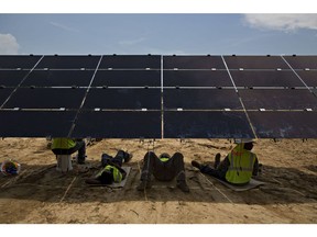 Workers take a break in the shade of a solar panel during construction of a Silicon Ranch Corp. solar generating facility in Milligan, Tennessee, U.S., on Thursday, May 24, 2018. Large oil companies in Europe are continuing to diversify their holdings and increase clean-energy investments. Royal Dutch Shell Plc agreed in January to buy a 44 percent stake in Silicon Ranch Corp., the Nashville-based owner and operator of U.S. solar plants.