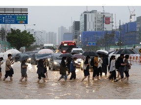 Pedestrians cross a flooded road at a junction in Gimpo, South Korea, on Tuesday, Aug. 9, 2022. At least eight people were killed and six people missing after one of the heaviest rain storms in 80 years hit Seoul, flooding streets and subway stations and causing blackouts. Photographer: SeongJoon Cho/Bloomberg