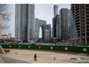 A pedestrian passes buildings in Beijing, China, on Thursday, Dec. 15, 2022. China's economic activity worsened in November before the government abruptly dropped its Covid Zero policy, with more disruption to growth likely as infections surge. Bloomberg Bloomberg