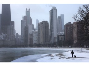 A man walks his dog along Chicago Lake near downtown as temperatures hover around -6 degrees Fahrenheit on December 22, 2022. The city faced wind chills as low as -40 degrees.