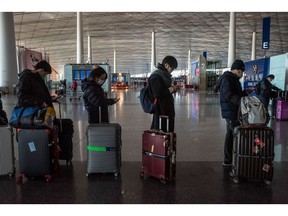 Passengers wait to check in at Beijing Capital International Airport