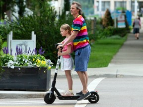 A father and daughter ride a Bird scooter in Edmonton.