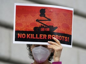 A woman holds up a sign while taking part in a demonstration about the use of robots by the San Francisco Police Department outside of City Hall in San Francisco, Monday, Dec. 5, 2022. The unabashedly liberal city of San Francisco became the unlikely proponent of weaponized police robots this week after supervisors approved limited use of the remote-controlled devices, addressing head-on an evolving technology that has become more widely available even if it is rarely deployed to confront suspects.