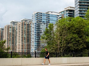 A pedestrian walks past condo buildings in Toronto.